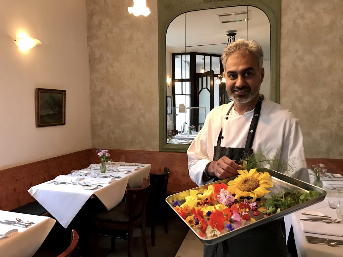 Jaspreet Dhaliwal-Wilmes steht mit einem Tablett Blüten in seinem Restaurant.