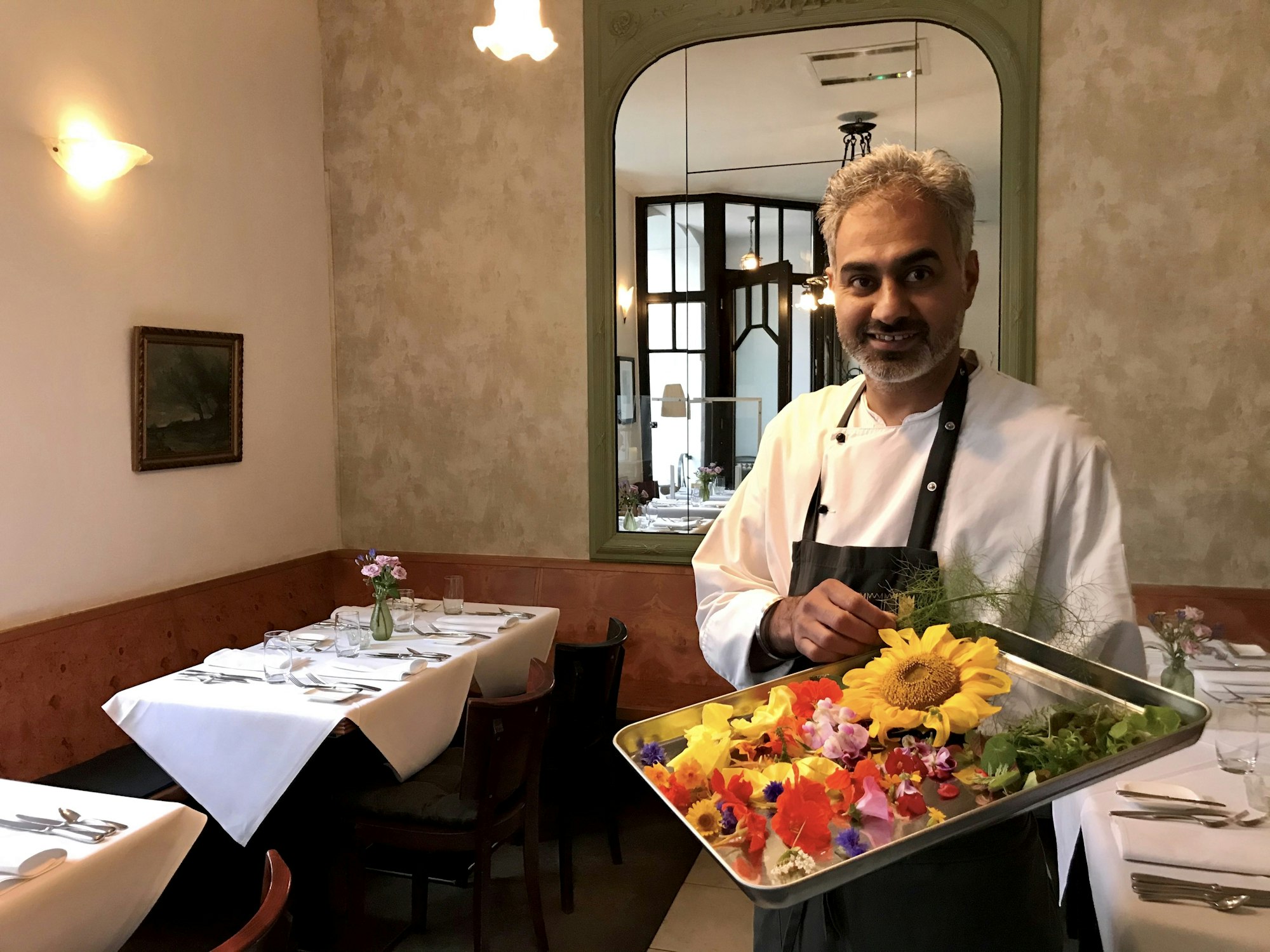 Jaspreet Dhaliwal-Wilmes steht mit einem Tablett Blüten in seinem Restaurant.