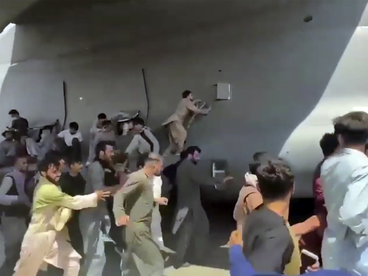 Hunderte Menschen laufen neben einer Boeing C-17 der United States Air Force, die auf dem Rollfeld des Kabul International Airport fährt.