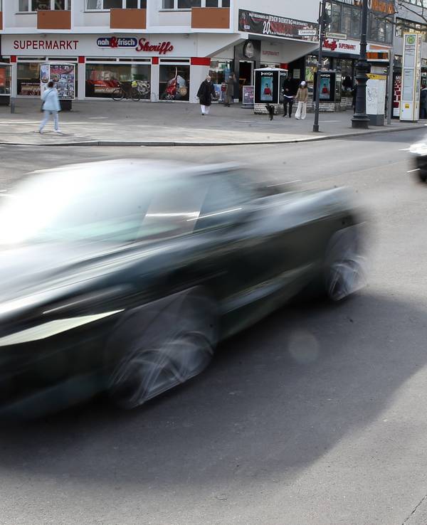 In rasantem Tempo fährt ein Auto über eine Straße.