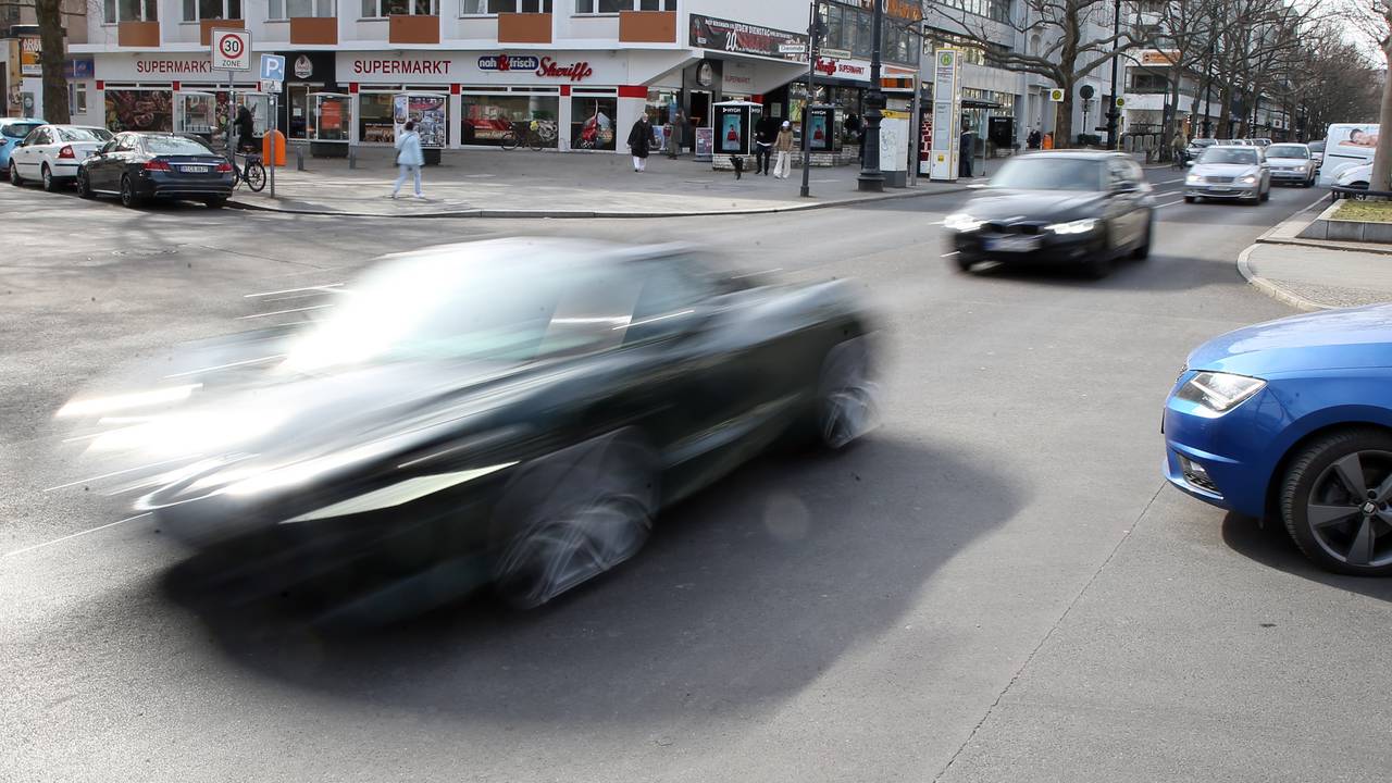In rasantem Tempo fährt ein Auto über eine Straße.
