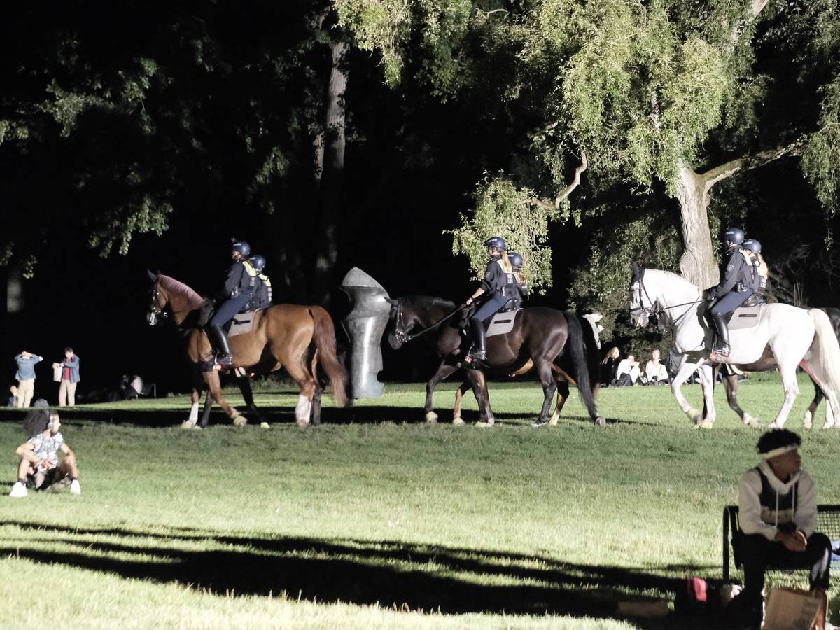 Polizisten auf Pferden reiten über die Grünfläche am Aachener Weiher.
