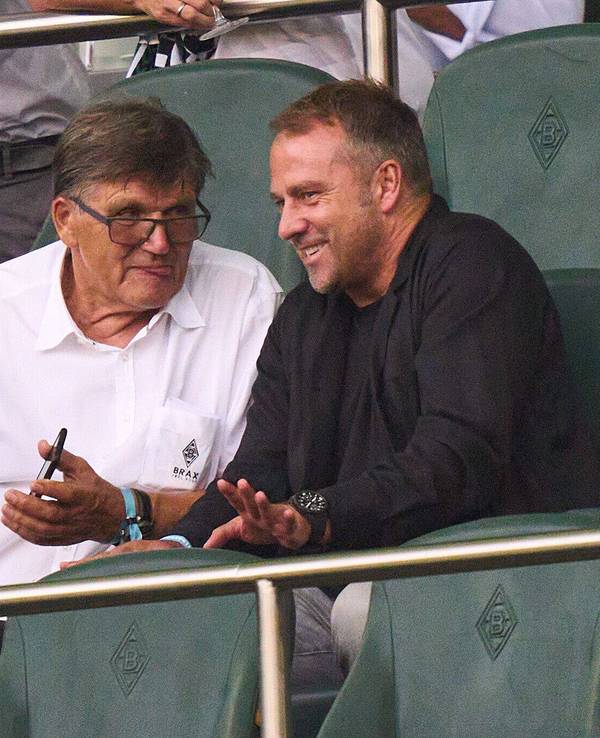 Hansi Flick sitzt in Mönchengladbach neben Hans Meyer auf der Tribüne.
