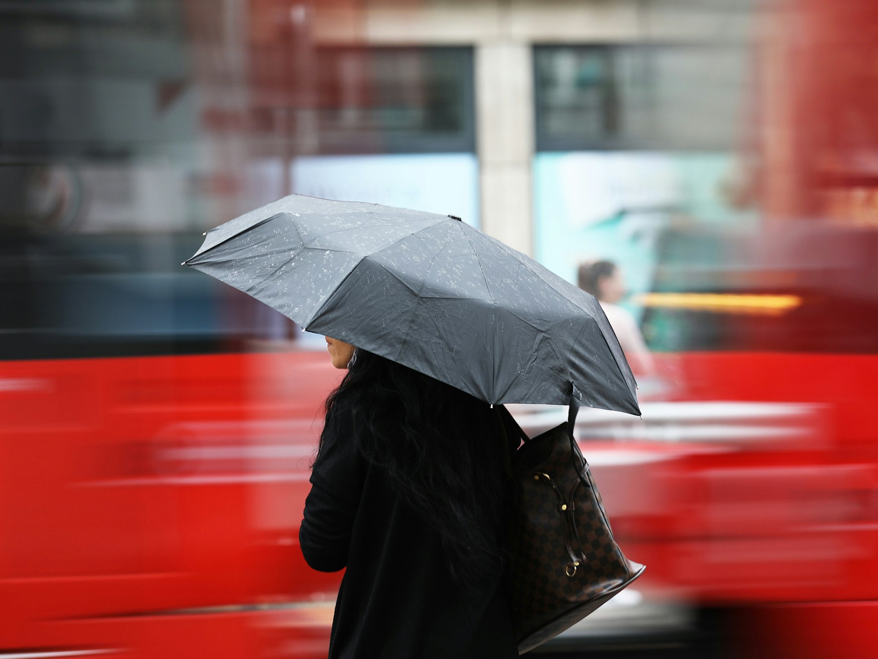 Eine Frau steht am Morgen (4. Juni 2020) mit einem Regenschirm an einer Straßenbahnhaltestelle. Regen bestimmt kurz vor dem Wochenende das Wetter in Nordrhein-Westfalen.