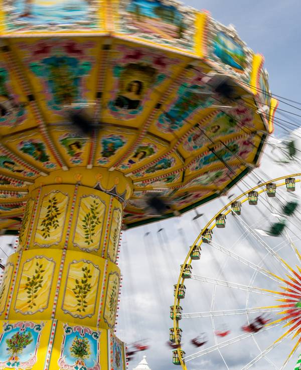 Besucherinnen und Besucher in einem Freizeitpark, im Hintergrund ein Riesenrad.