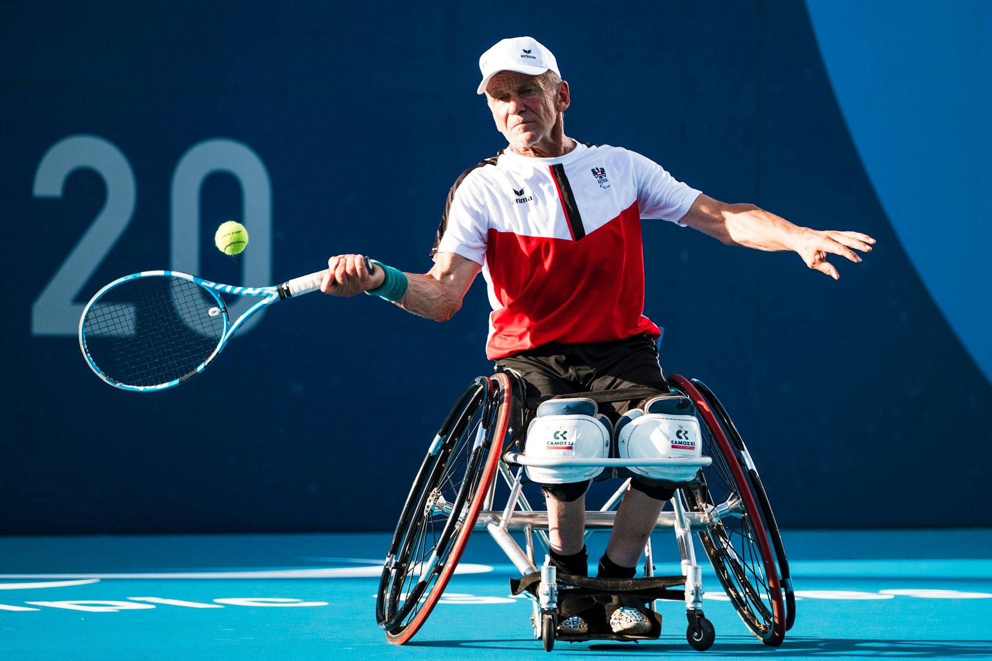 Martin Legner schlägt sitzend mit dem Tennisschläger gegen den Ball.