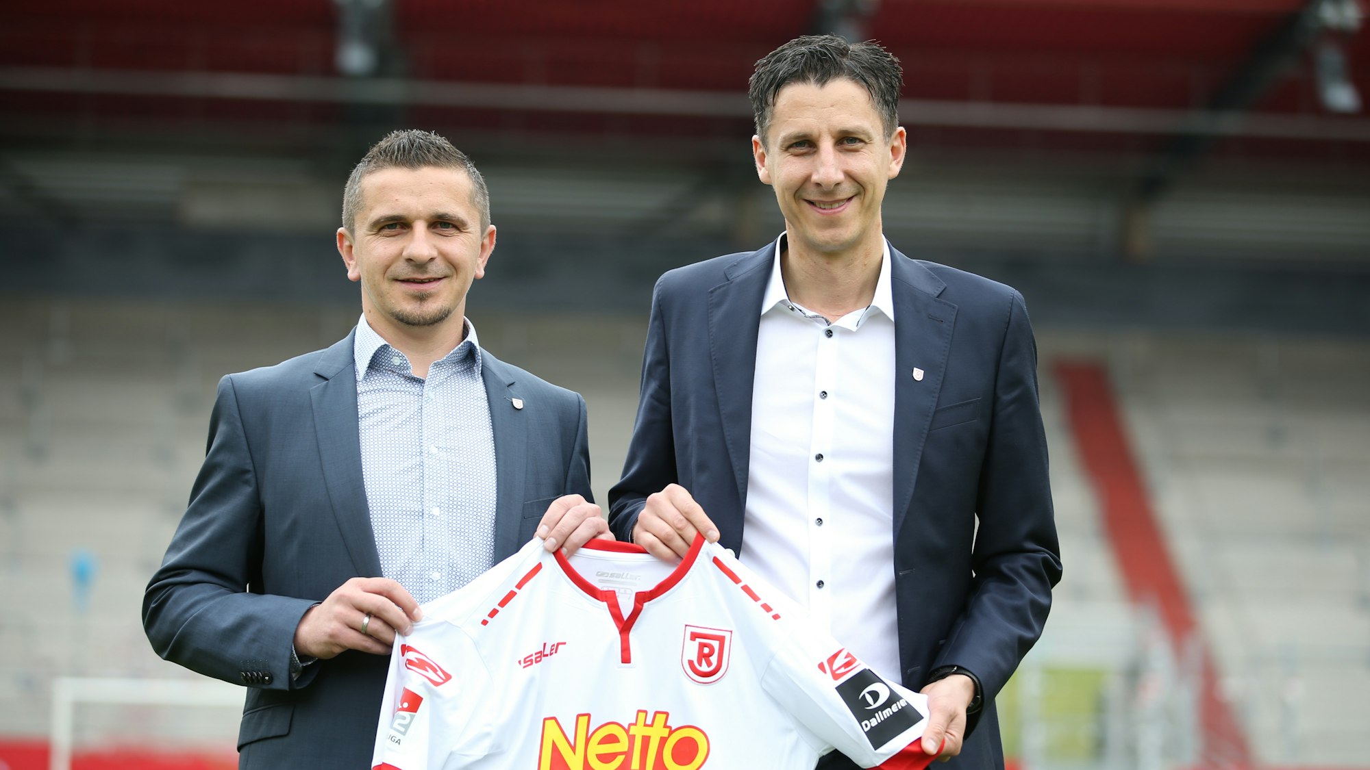 Christian Keller und Mersad Selimbegovic posieren mit dem Trikot von Jahn Regensburg.