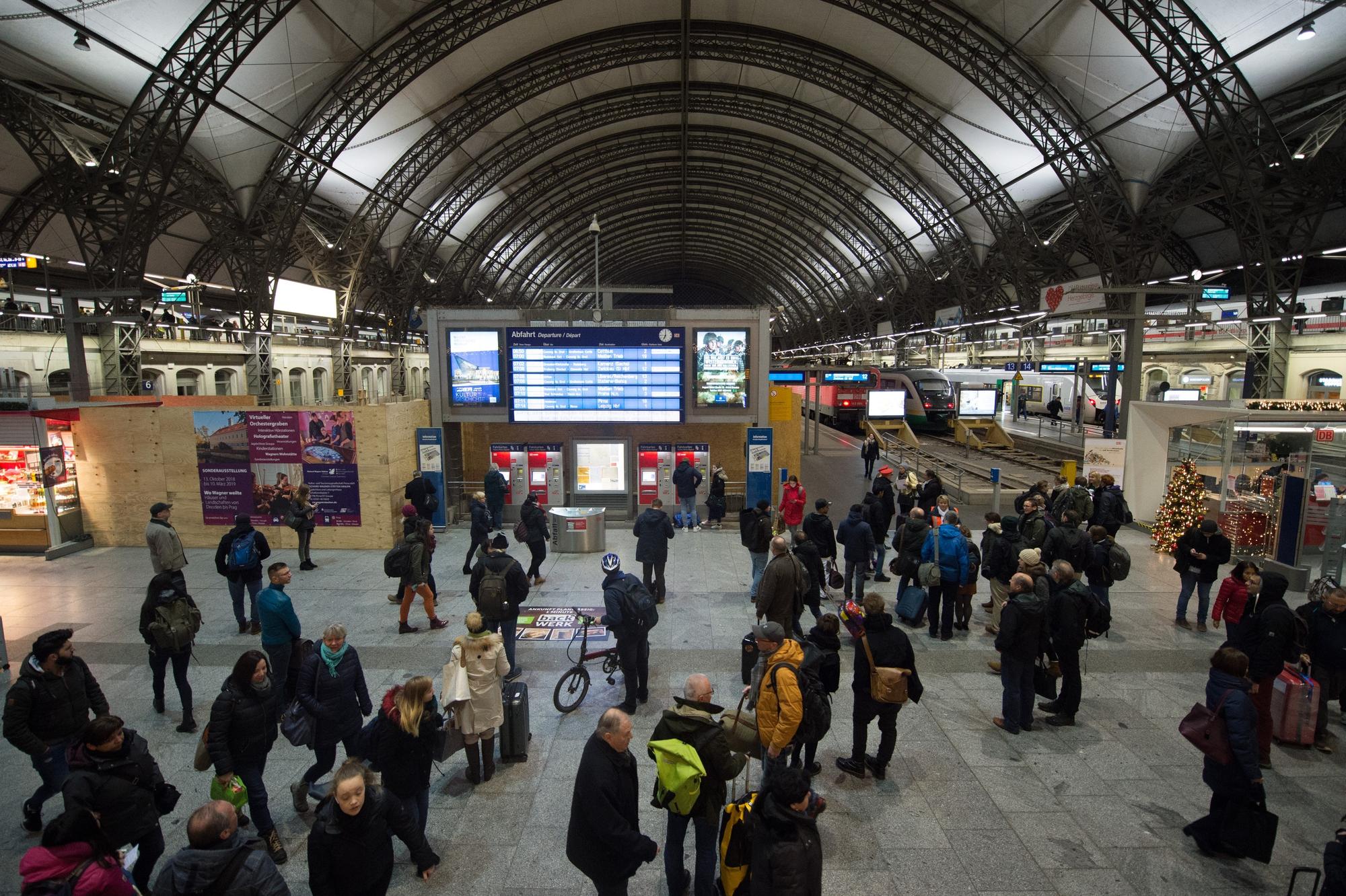 Zugreisende stehen im Dezember 2018 im Dresdner Hauptbahnhof vor einer Anzeigetafel.