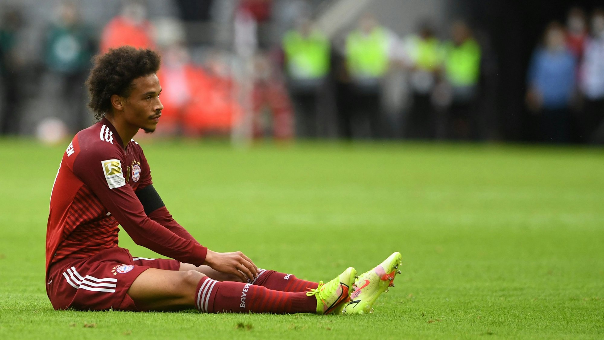 Bayern Münchens Leroy Sané sitzt beim Spiel gegen Köln auf dem Rasen.
