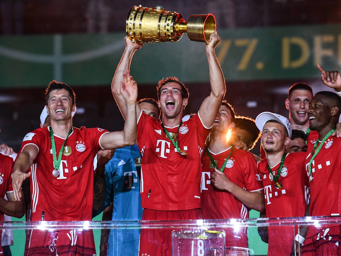 Leon Goretzka hält den DFB-Pokal mit seinen Händen in den Nachthimmel, neben ihm feiert Robert Lewandowski.