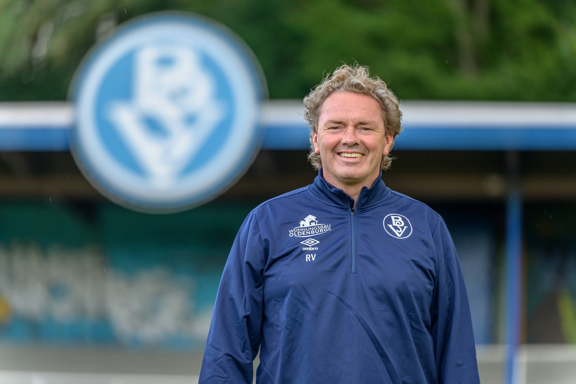Ralf Voigt steht im Trainingsanzug im Stadion und blickt in die Kamera.