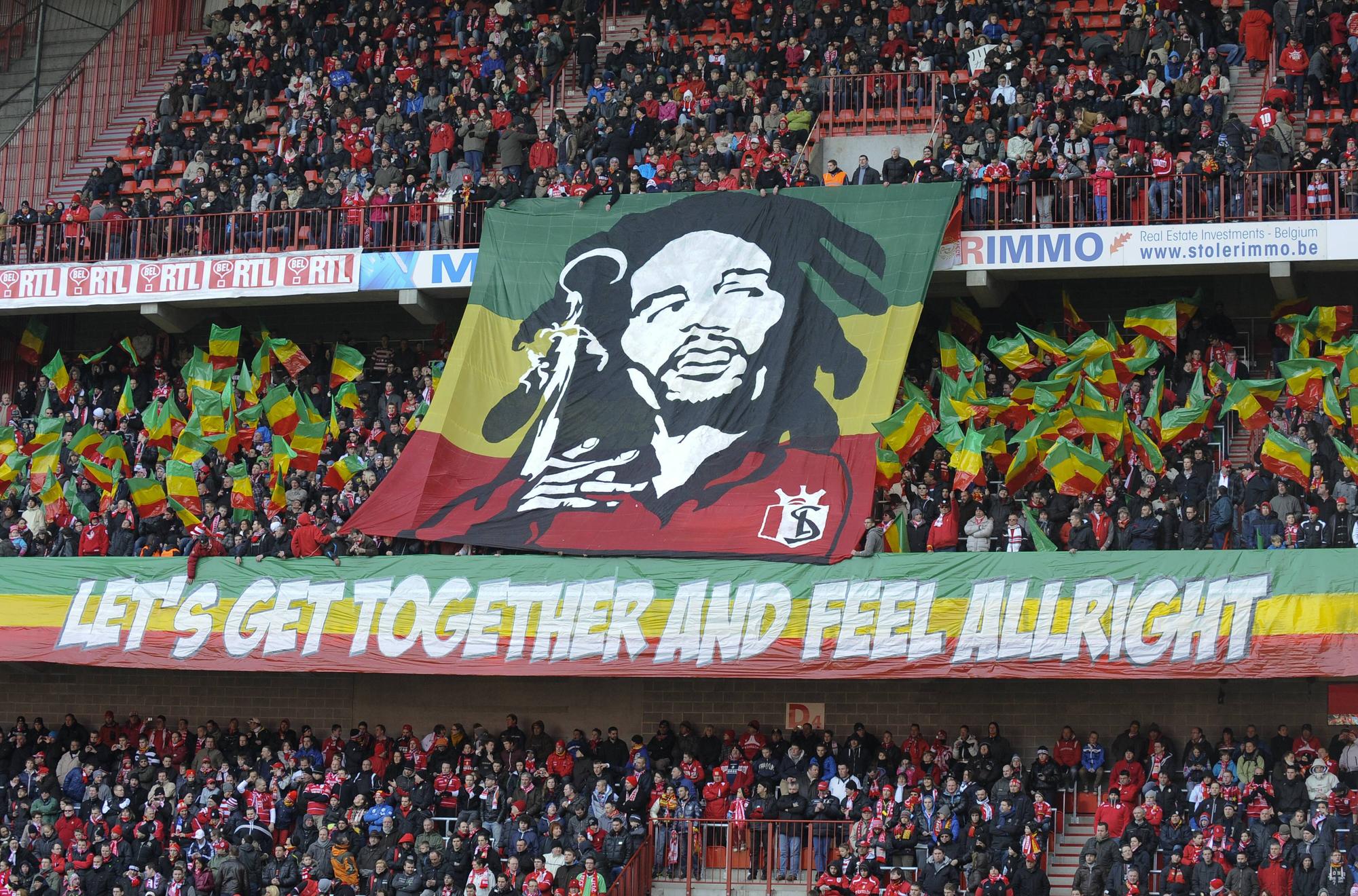 Fans von Standard Lüttich schwenken rot-gelb-grüne Fähnchen und zeigen ein Konterfei von Bob Marley im Trikot des Vereins.