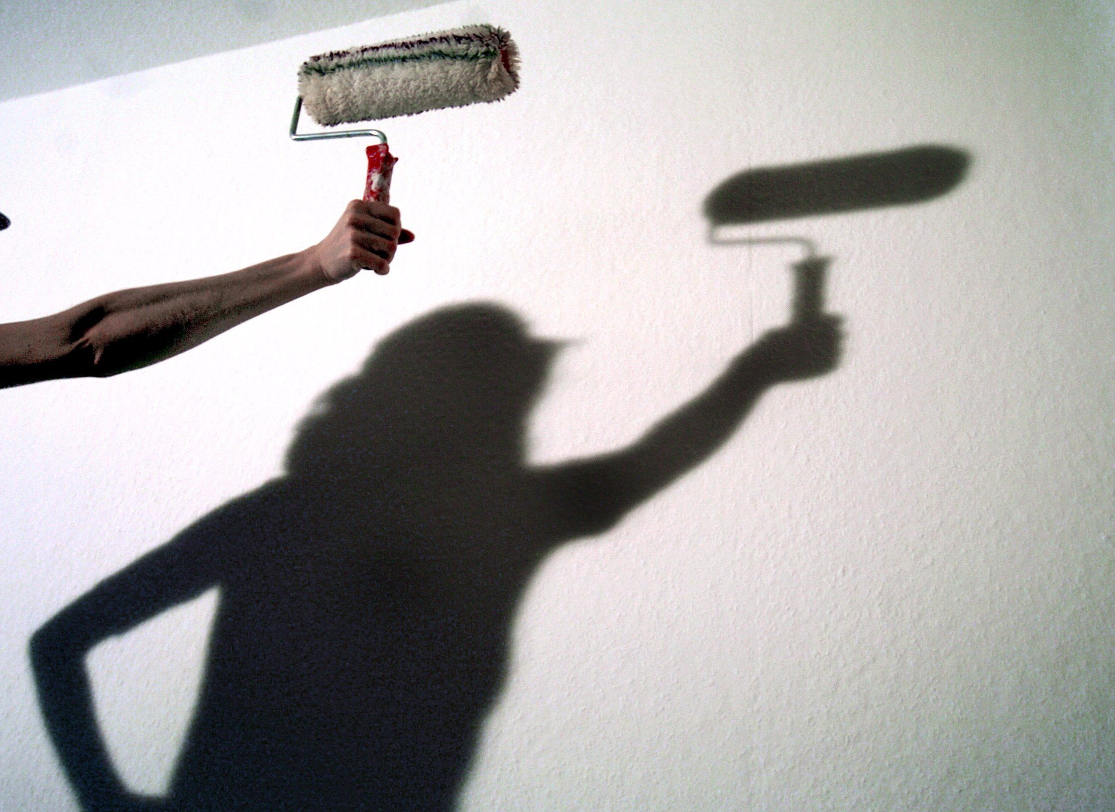 Der Schatten einer Frau mit einer Anstreicherrolle zeichnet sich an einer Wand ab, aufgenommen im Dezember 2003