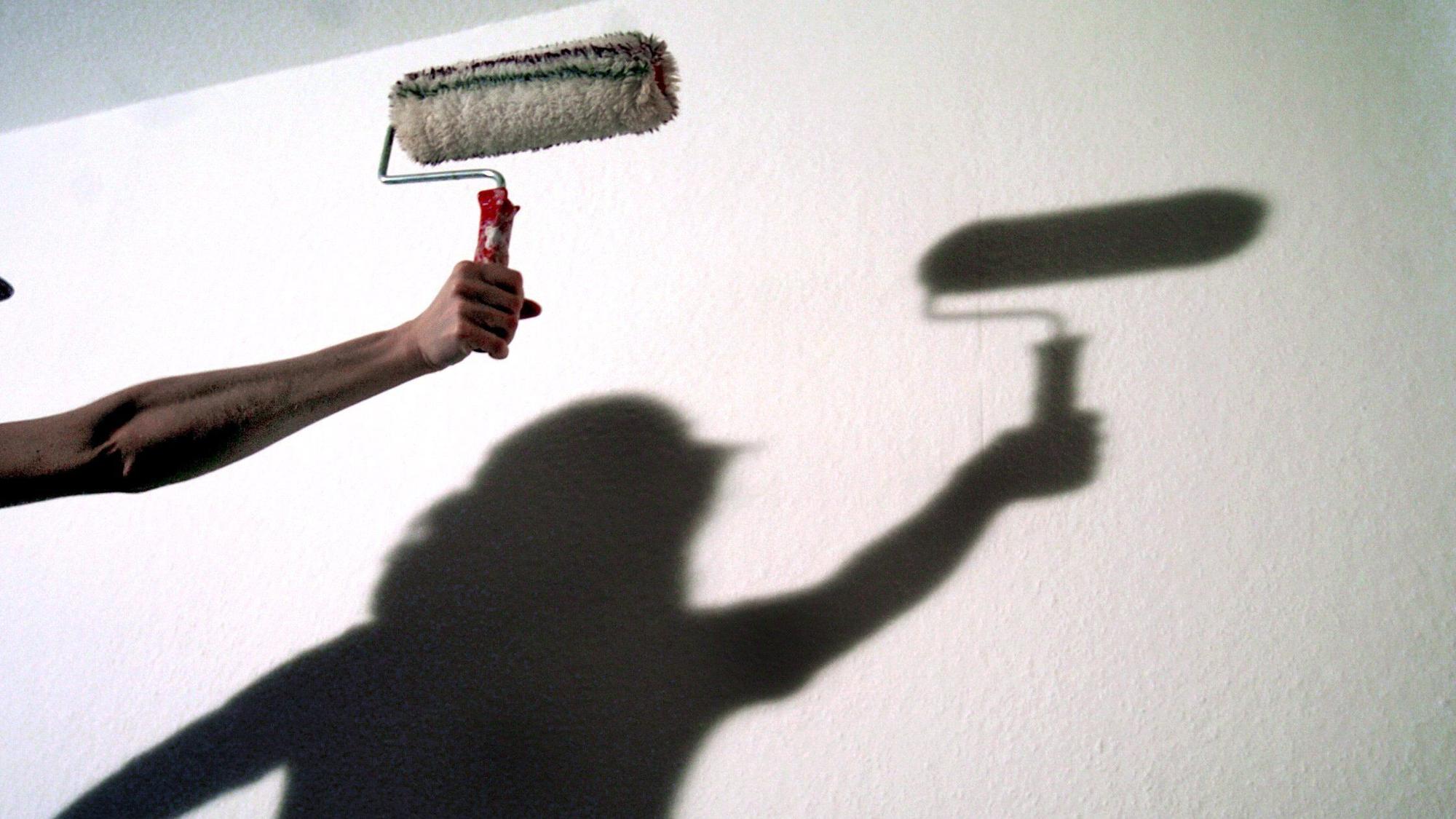 Der Schatten einer Frau mit einer Anstreicherrolle zeichnet sich an einer Wand ab, aufgenommen im Dezember 2003