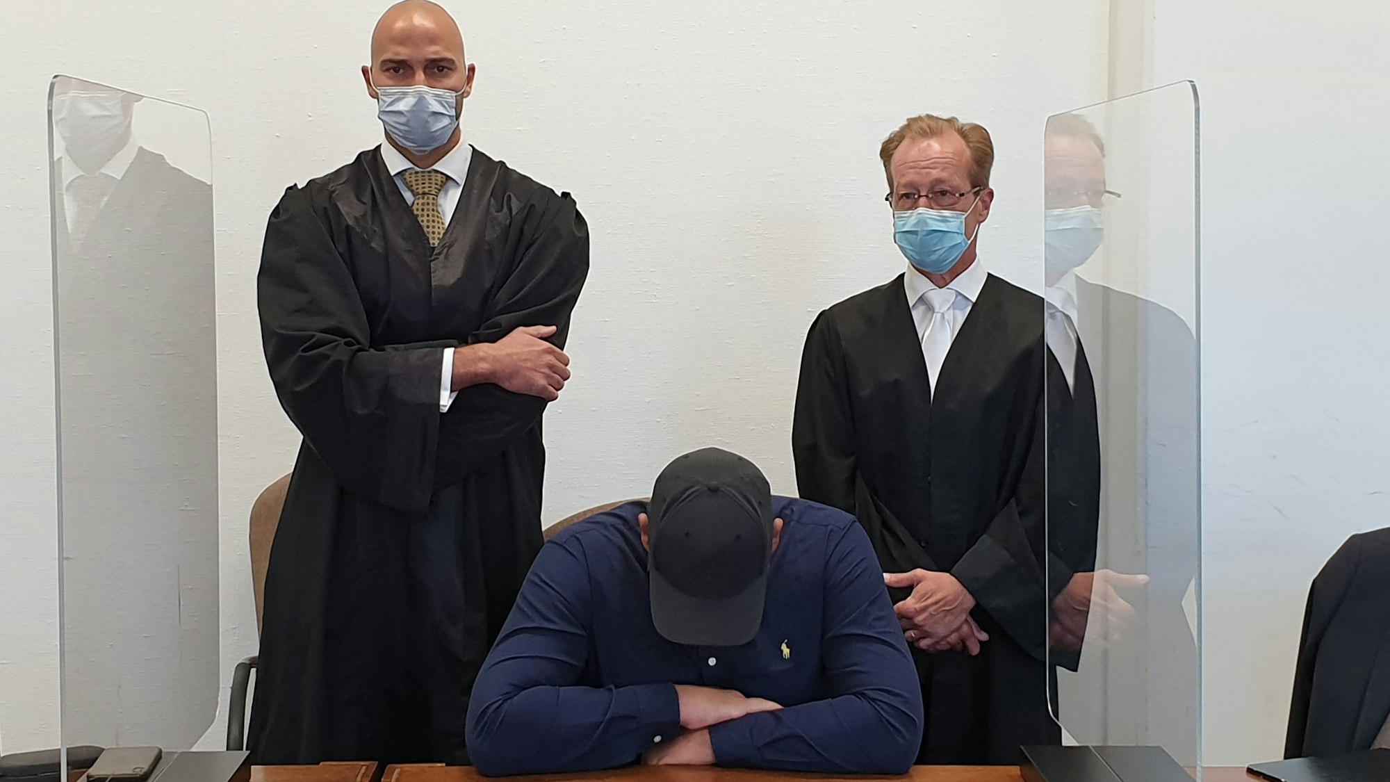 Das Hells Angels-Mitglied sitzt auf der Anklagebank, hinter ihm stehen seine beiden Anwälte.