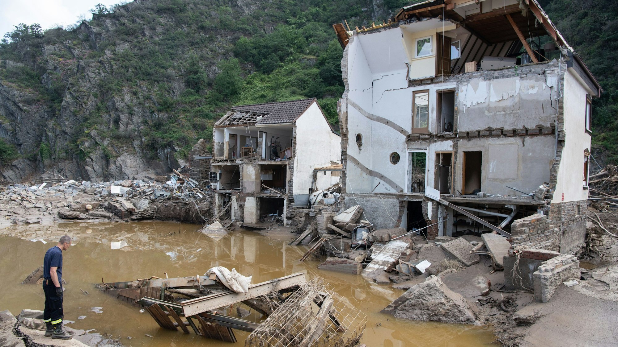 Ein Feuerwehrmann steht im Dorf Mayschoß vor einem völlig zerstörten Haus. Der Klimawandel erhöht laut einer Studie die Wahrscheinlichkeit extremer Regenfälle und damit von Hochwasserkatastrophen, wie sie im Juli in Rheinland-Pfalz und Nordrhein-Westfalen vielen Menschen das Leben gekostet hat.