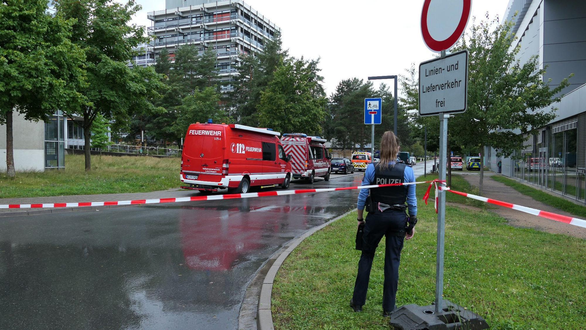 Eine Polizistin steht vor der TU Darmstadt. Das Areal ist weiträumig abgesperrt.
