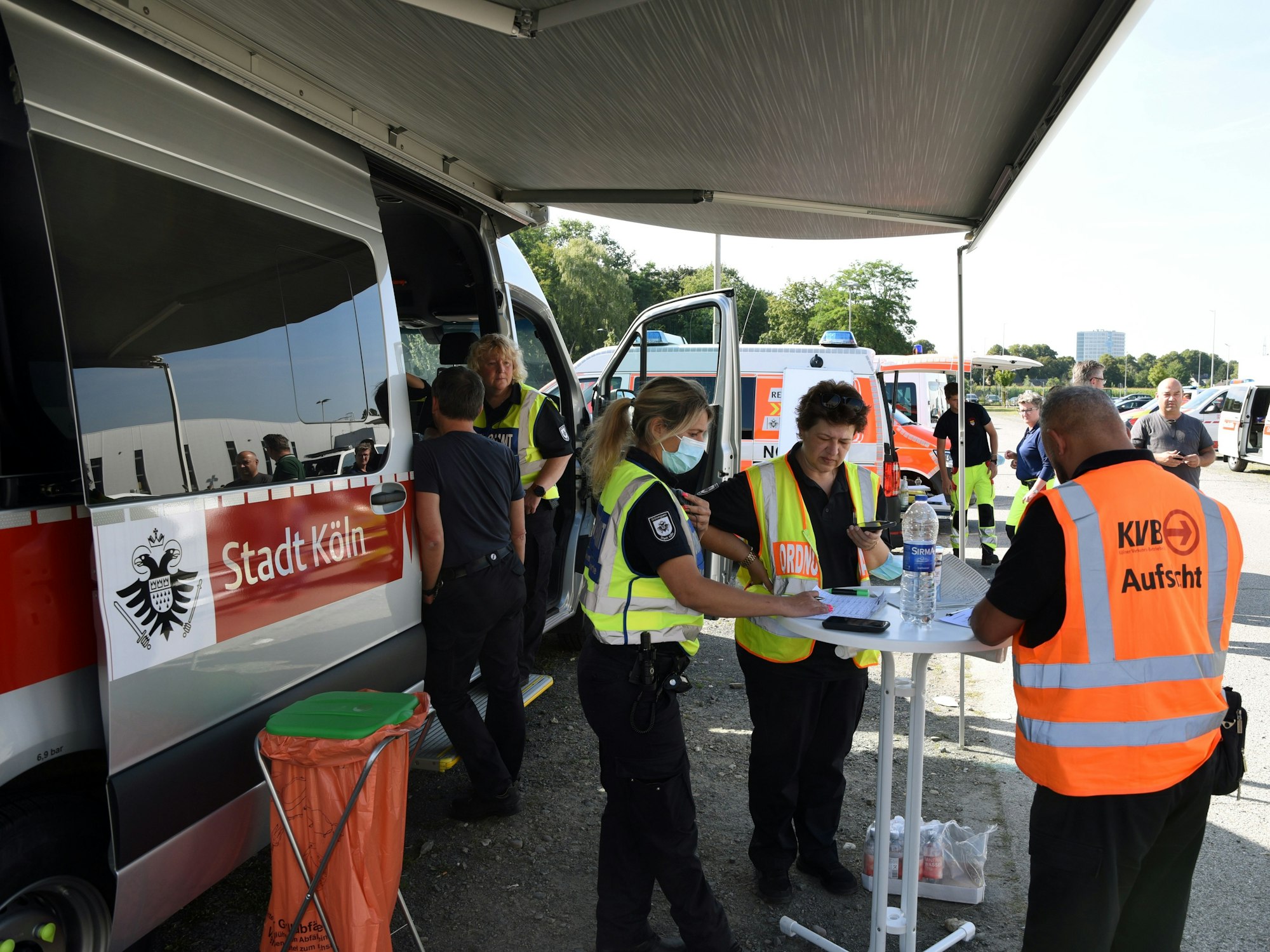 Vor einem Fahrzeug der Stadt Köln stehen mehrere Einsatzkräfte.