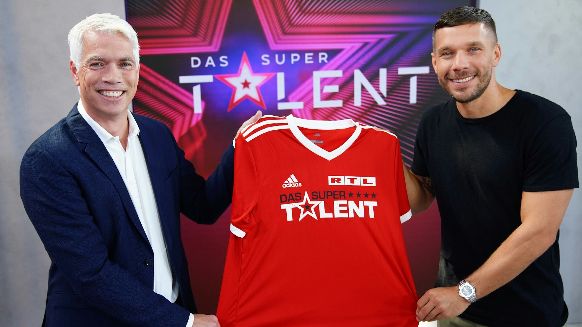 Die Freude war groß bei RTL Ende Juni, als klar war, dass Fußball-Weltmeister Lukas Podolski (r., hier zusammen mit Henning Tewes, Geschäftsführer RTL) Juror beim „Supertalent“ 2021 sein soll. Nach Podolskis positivem Corona-Test ist der weitere Plan für die Produktion nun aber offen.