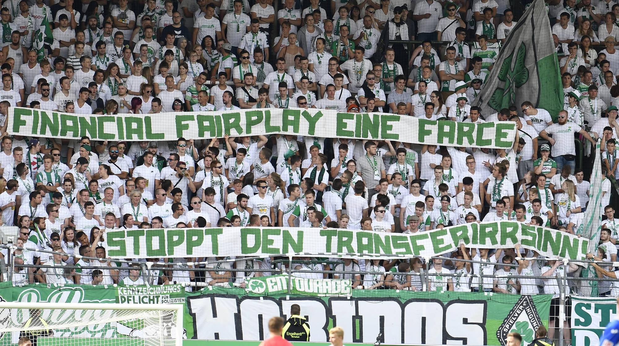 Fans von Greuther Fürth zeigen ein Banner mit dem Schriftzug „Financial Fairplay eine Farce, stoppt den Transferwahnsinn!“