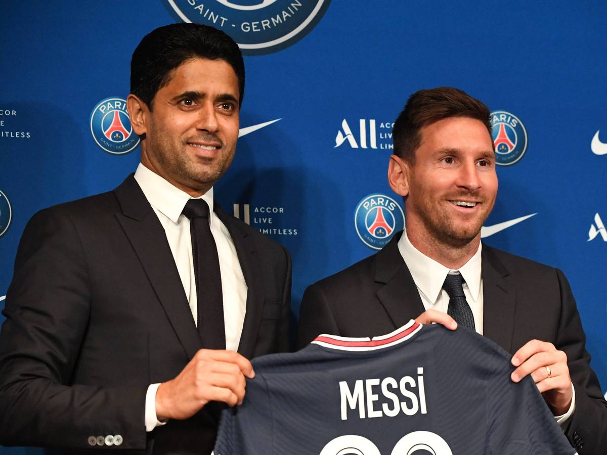 Lionel Messi und PSG-Präsident Nasser Al-Khelaifi halten ein PSG-Trikot hoch.
