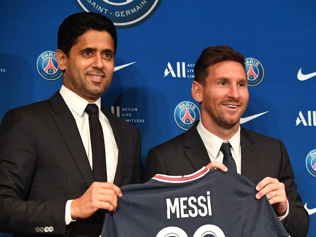 Lionel Messi und PSG-Präsident Nasser Al-Khelaifi halten ein PSG-Trikot hoch.