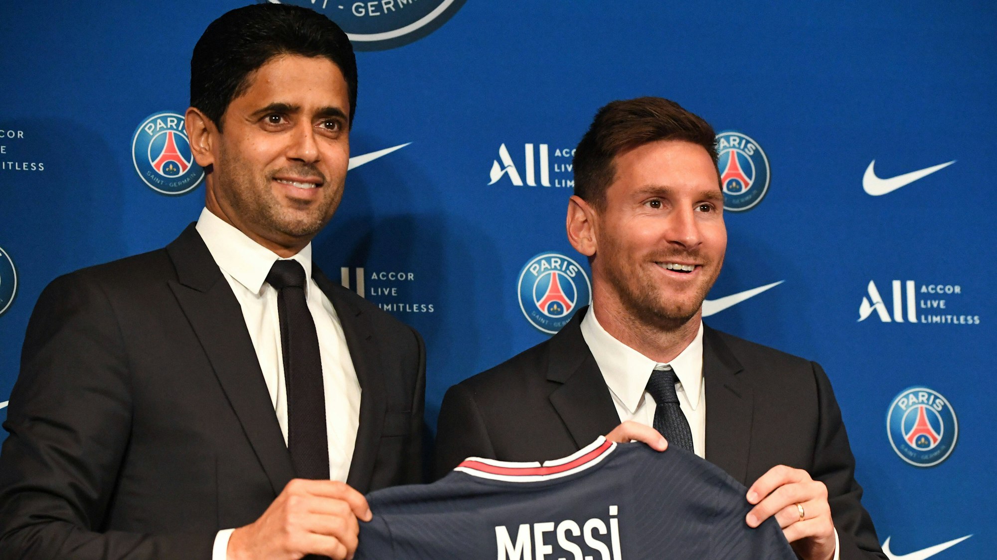 Lionel Messi und PSG-Präsident Nasser Al-Khelaifi halten ein PSG-Trikot hoch.