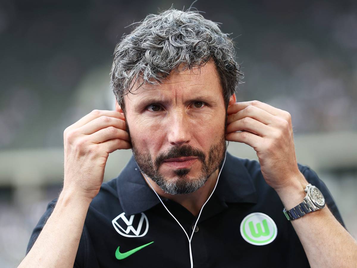 Wolfsburgs Trainer Mark van Bommel setzt Kopfhörer vor einem Interview auf.