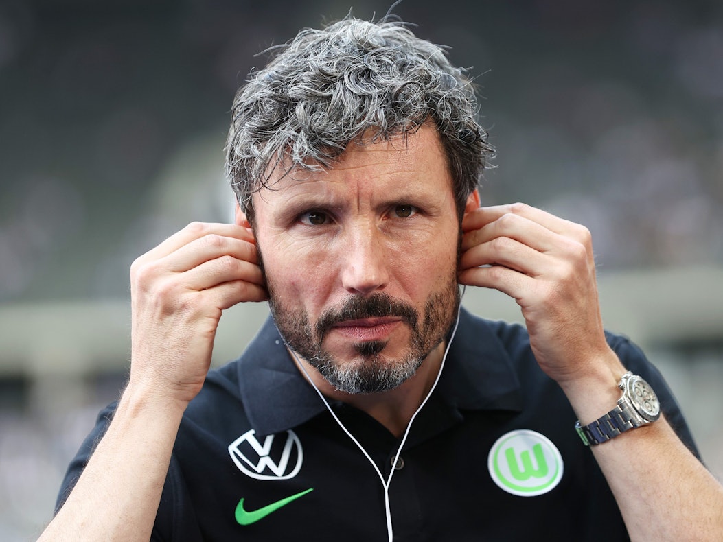 Wolfsburgs Trainer Mark van Bommel setzt Kopfhörer vor einem Interview auf.