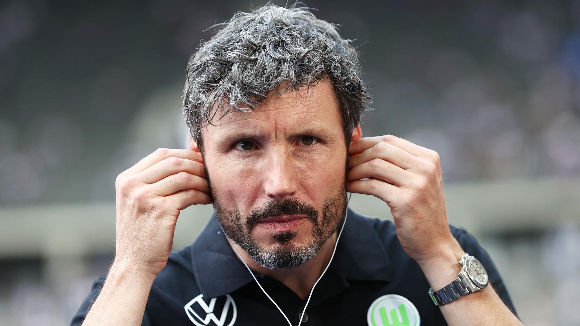 Wolfsburgs Trainer Mark van Bommel setzt Kopfhörer vor einem Interview auf.