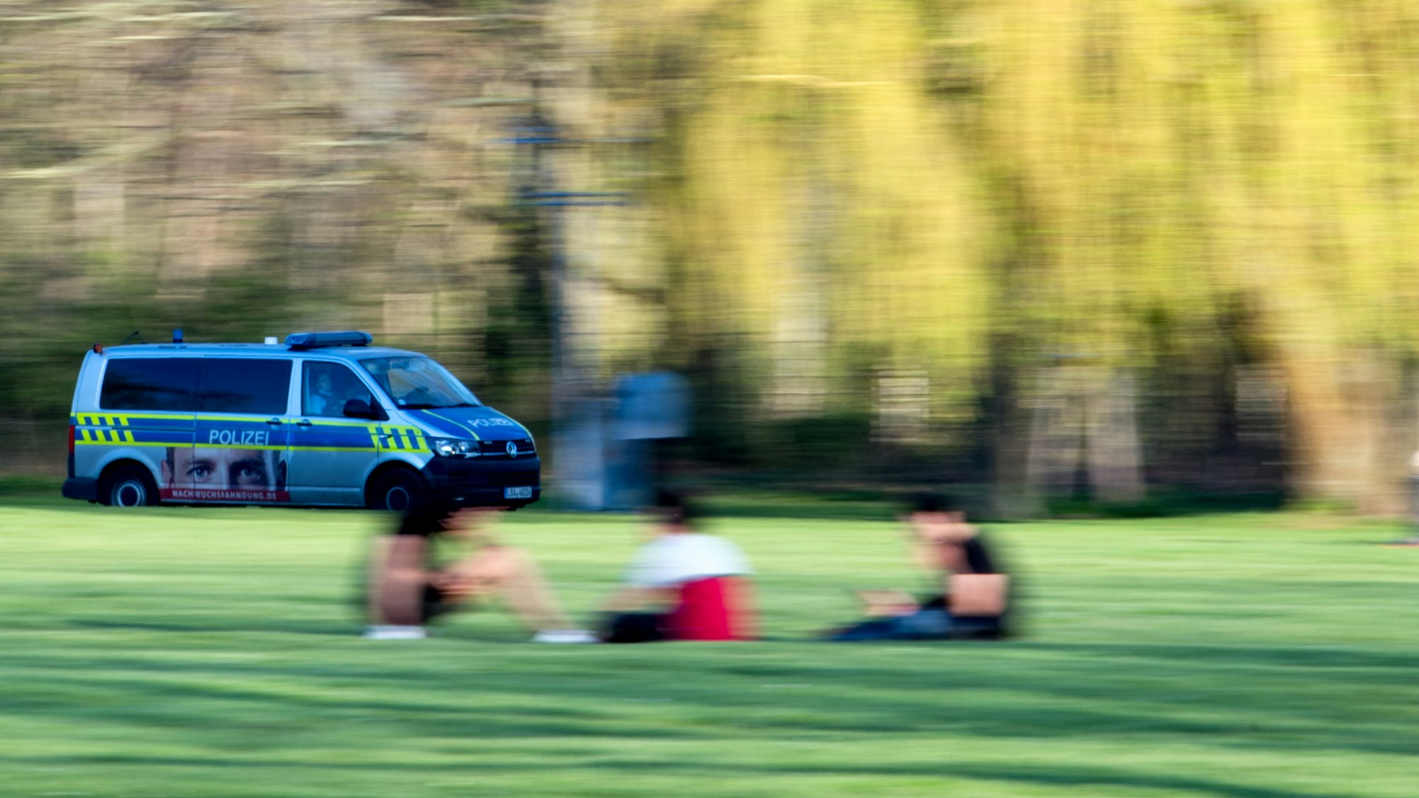 Ein Polizeifahrzeug fährt durch einen Park.