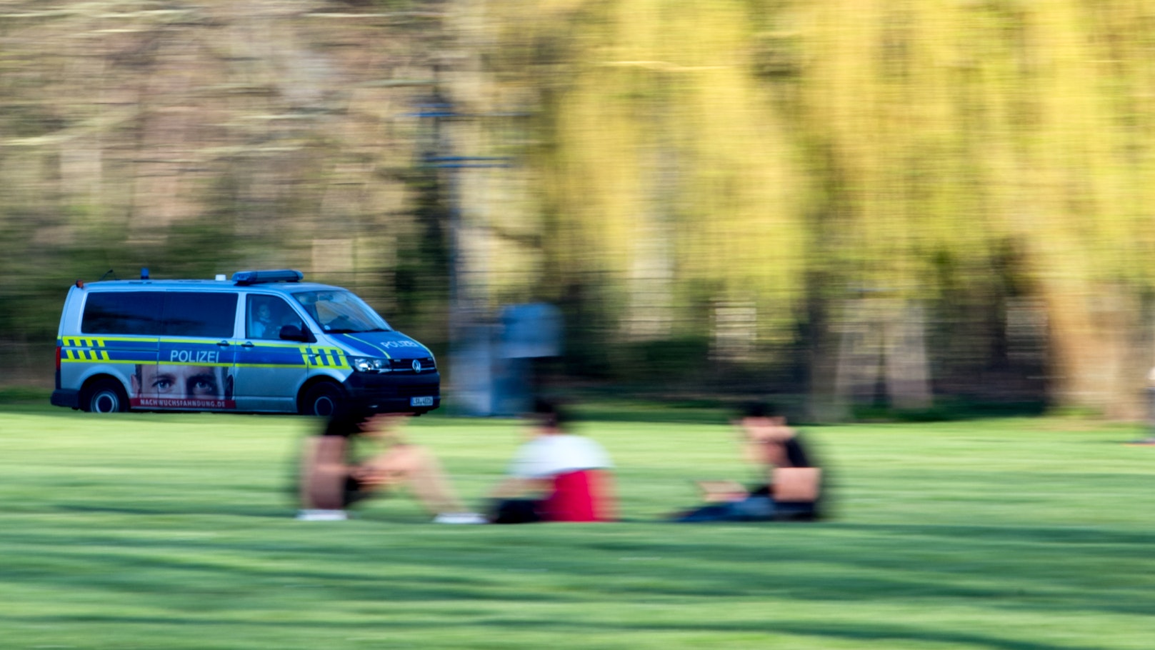 Ein Polizeifahrzeug fährt durch einen Park.