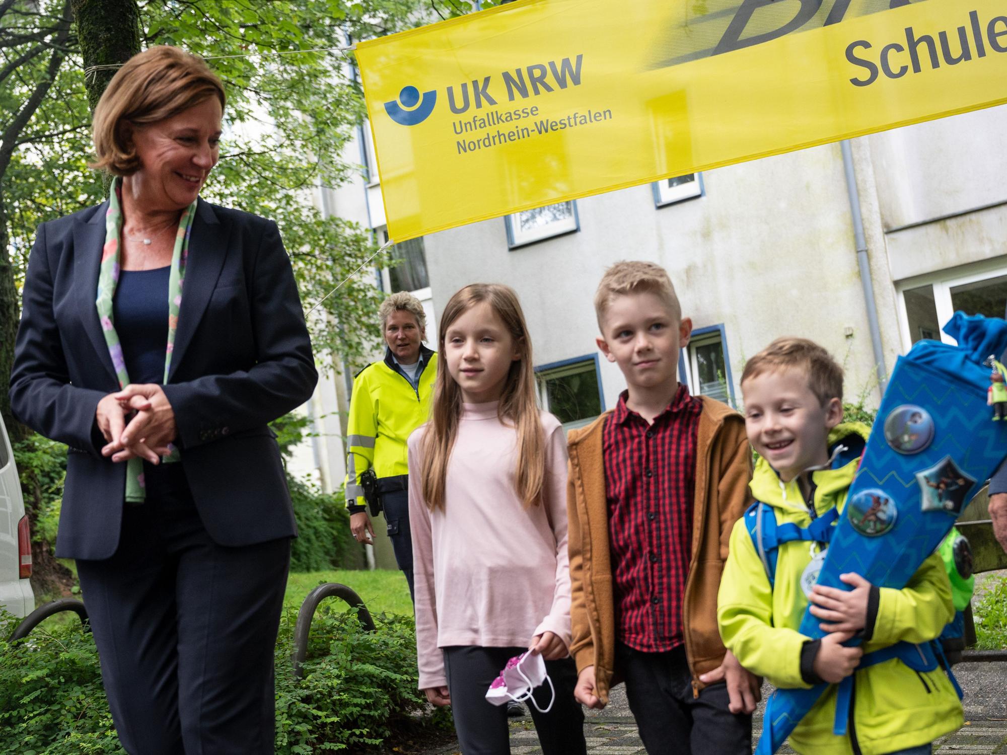 Yvonne Gebauer überquert mit Schülerinnen und Schülern der Grundschule Ferdinand-Lasalle die Straße vor der Schule.