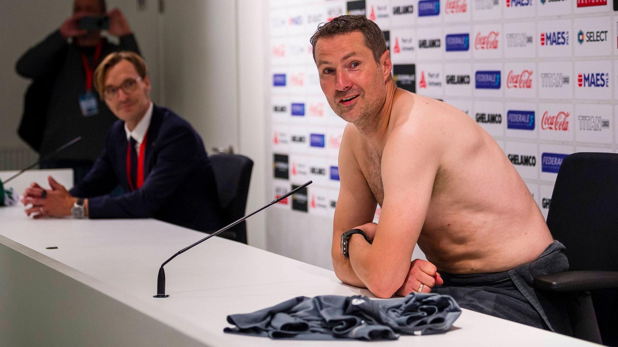 Brian Priske spricht mit nacktem Oberkörper auf der Pressekonferenz von Royal Antwerpen.