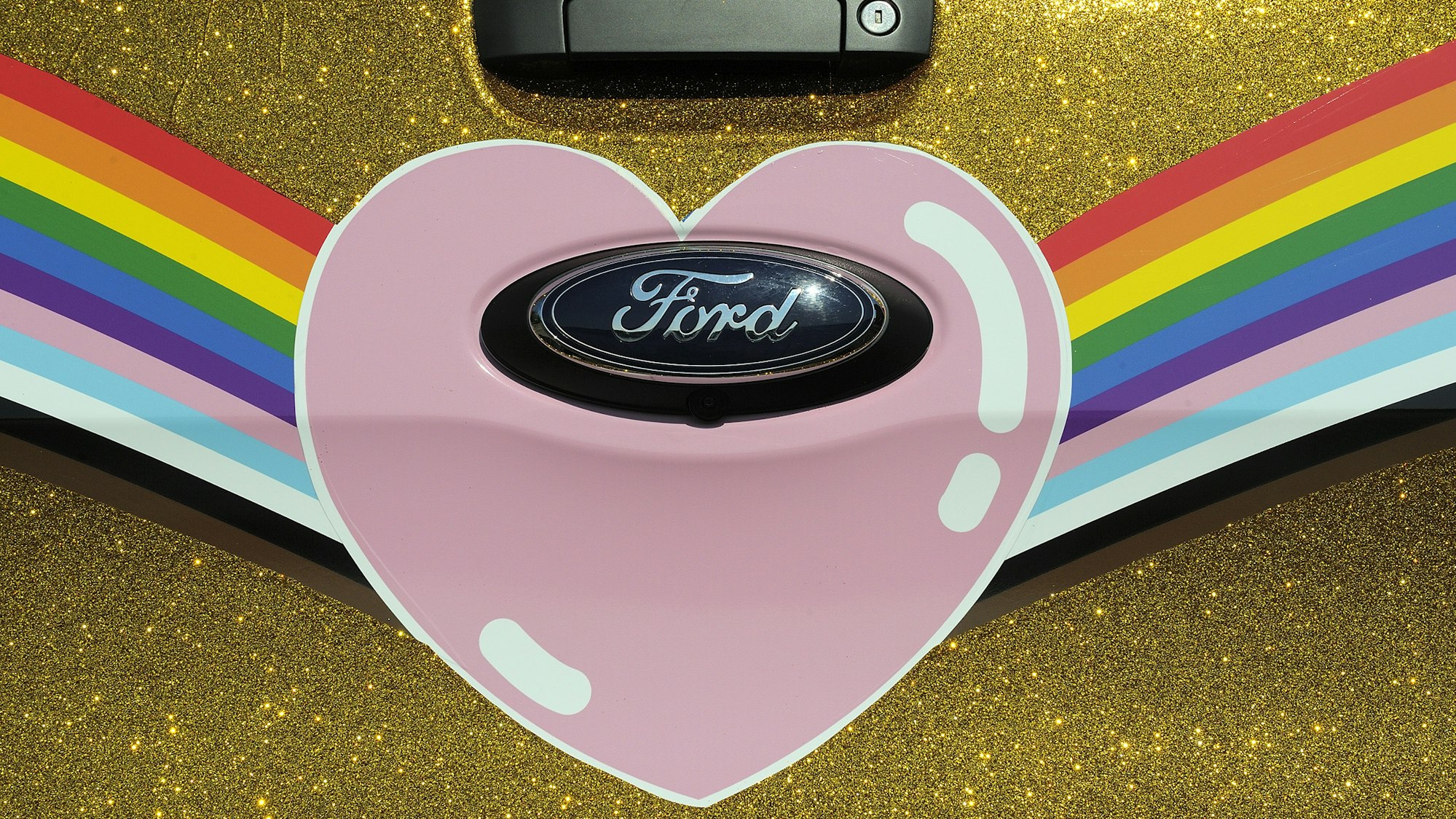 Das Heck des Ford „Very Gay Raptor“ in Regenbogenfarben, Goldstaub und mit Herz um das Ford-Logo.
