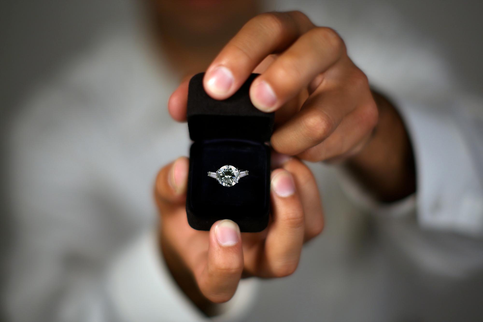 Ein Mann hält eine Ringschachtel mit einem Diamant-Ring in der Hand.