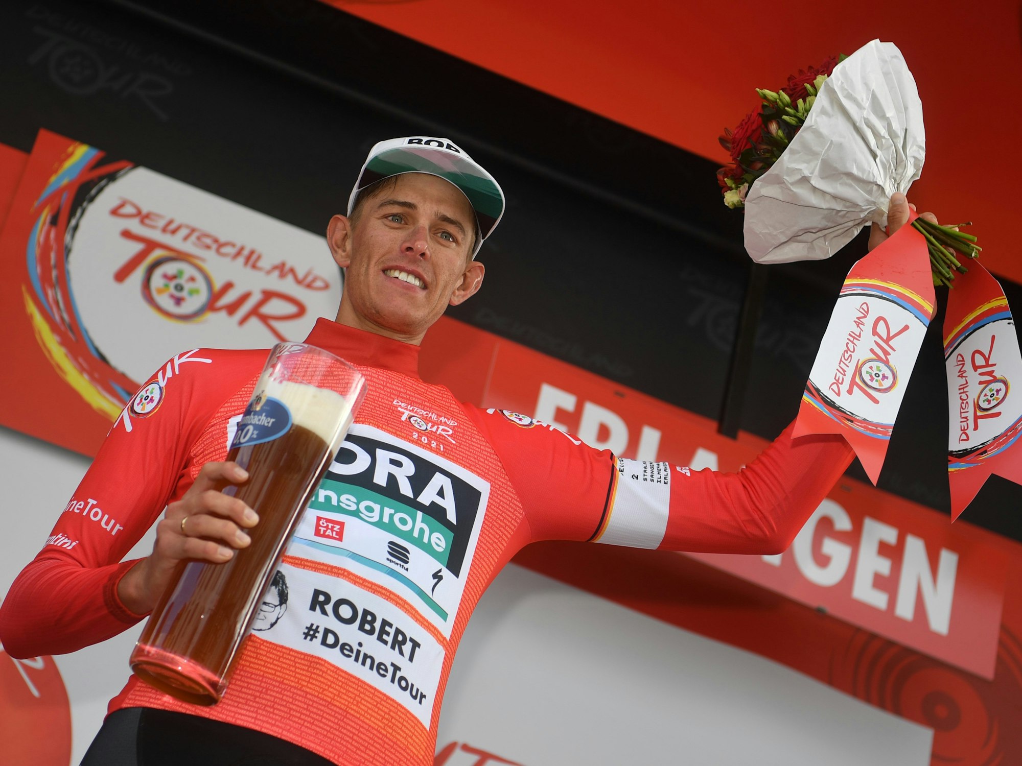 Nils Politt vom Team Bora-Hansgrohe jubelt nach der Etappe im Roten Trikot des Gesamtführenden auf dem Podium.