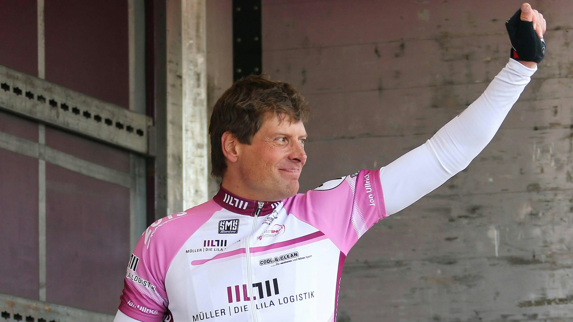 Jan Ullrich reckt am Rande eines Radrennens die Faust in die Luft.