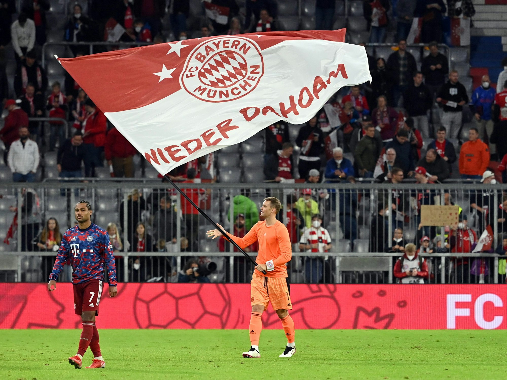 Münchens Torwart Manuel Neuer (M) schwenkt nach dem Spiel eine Bayern-Fahne mit dem Schriftzug "Wieder Dahoam".
