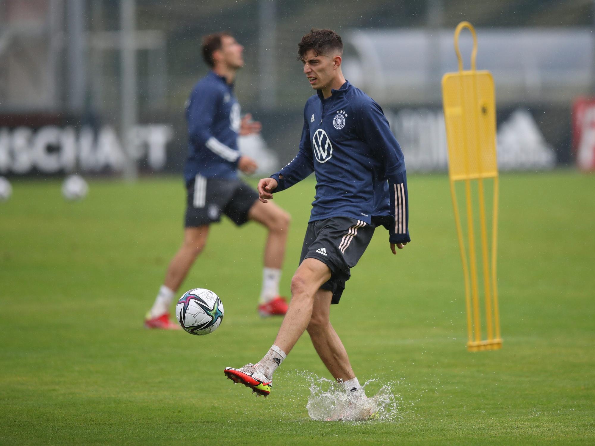 Kai Havertz spielt beim Training der Nationalmannschaft den Ball auf dem nassen Platz.