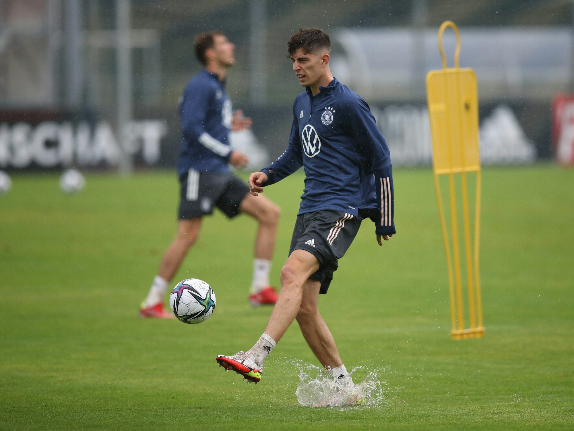 Kai Havertz spielt beim Training der Nationalmannschaft den Ball auf dem nassen Platz.