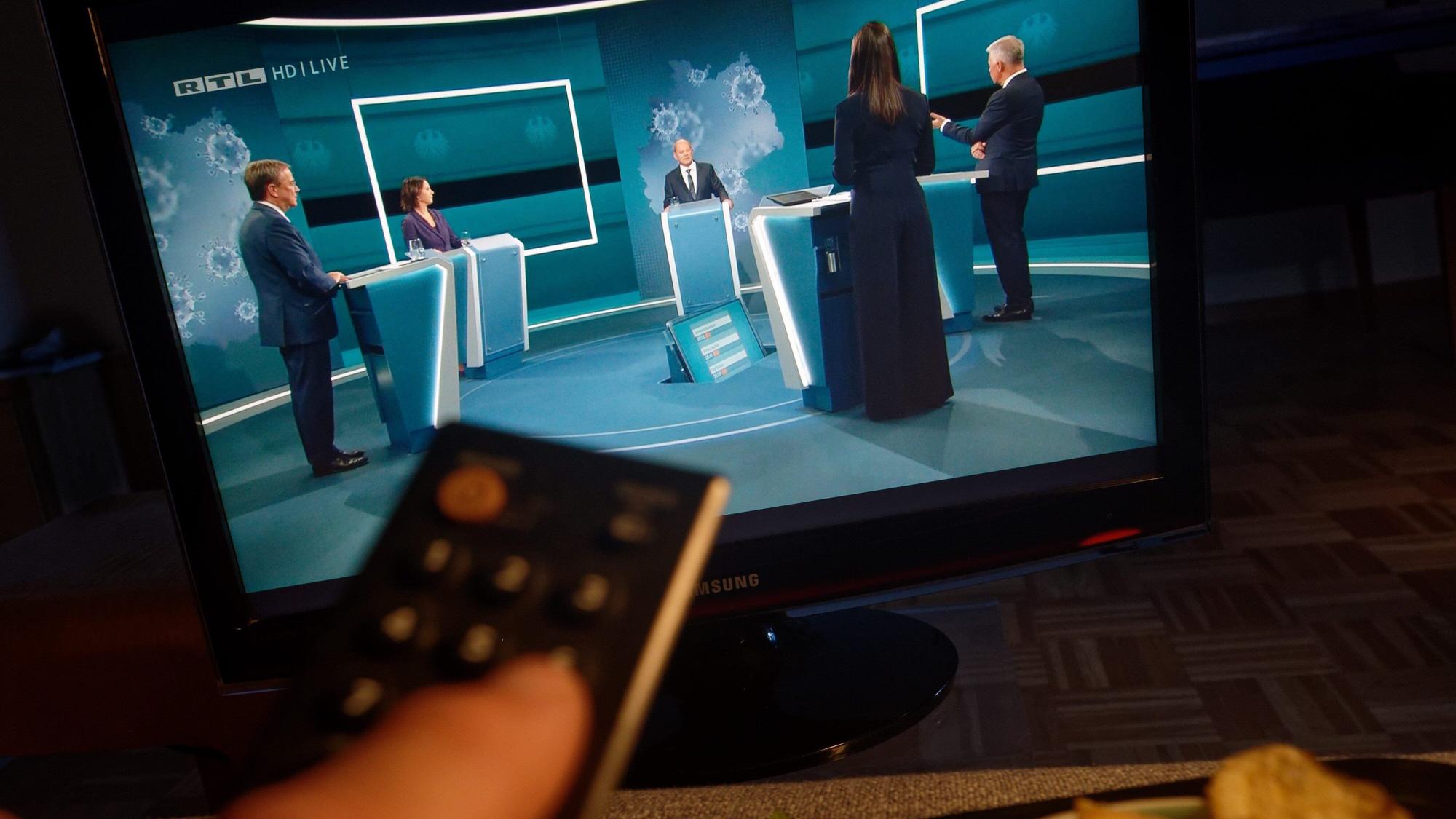 Auf einem Fernseher in einem Wohnzimmer ist „Das Triell“ auf RTL zu sehen. Die Kanzlerkandidaten von Bündnis 90/Grüne, CDU und SPD, Laschet, Baerbock und Scholz (v.l.), treffen in einer ersten TV-Diskussion aufeinander.