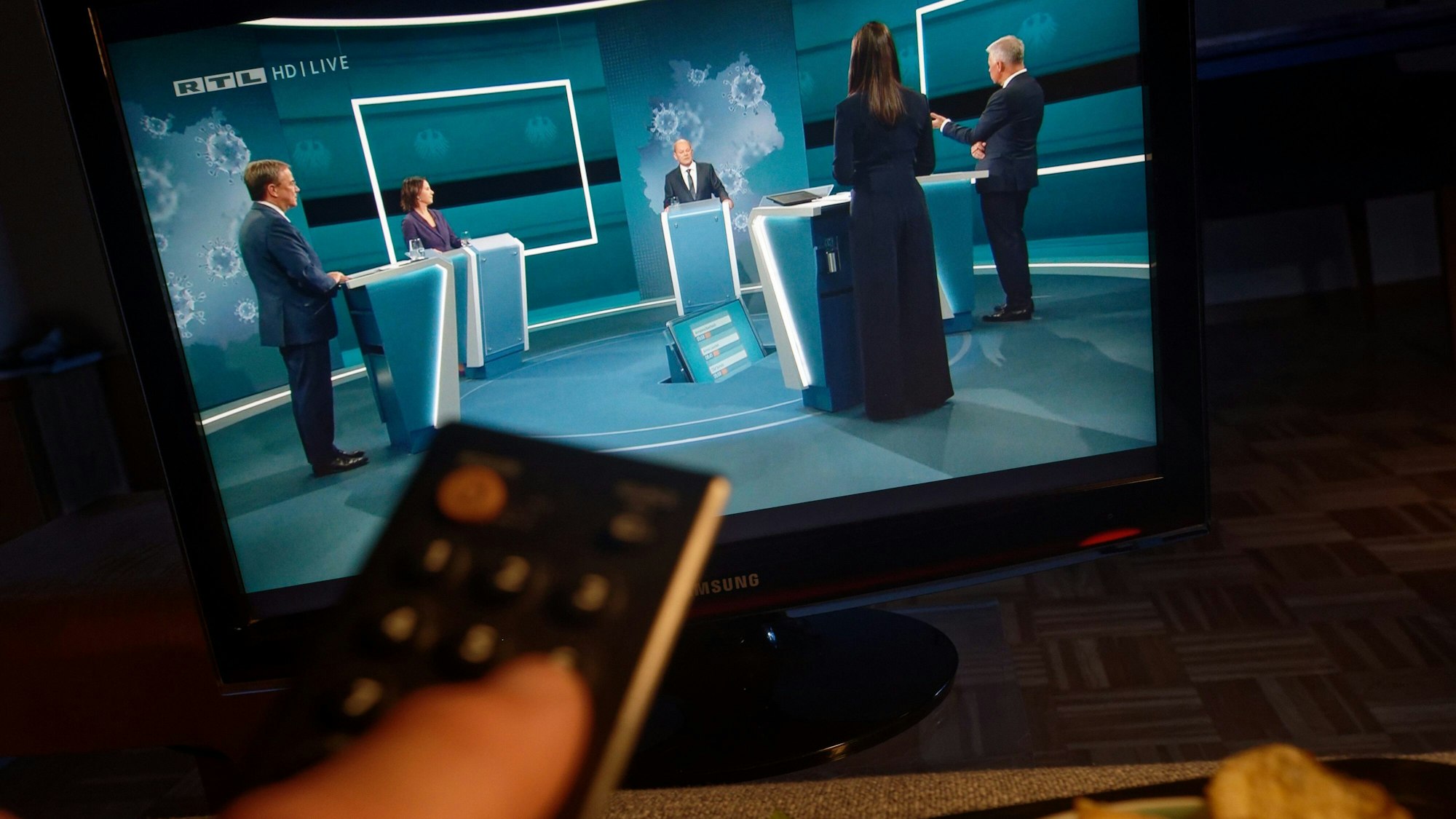 Auf einem Fernseher in einem Wohnzimmer ist „Das Triell“ auf RTL zu sehen. Die Kanzlerkandidaten von Bündnis 90/Grüne, CDU und SPD, Laschet, Baerbock und Scholz (v.l.), treffen in einer ersten TV-Diskussion aufeinander.