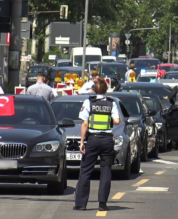 Eine Polizistin steht vor den Fahrzeugen eines angehaltenen türkischen Hochzeitskorsos.