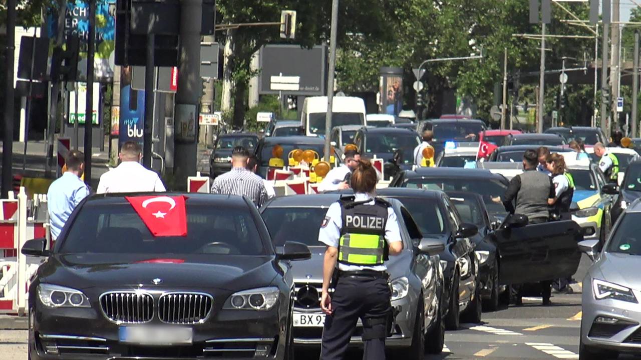 Eine Polizistin steht vor den Fahrzeugen eines angehaltenen türkischen Hochzeitskorsos.