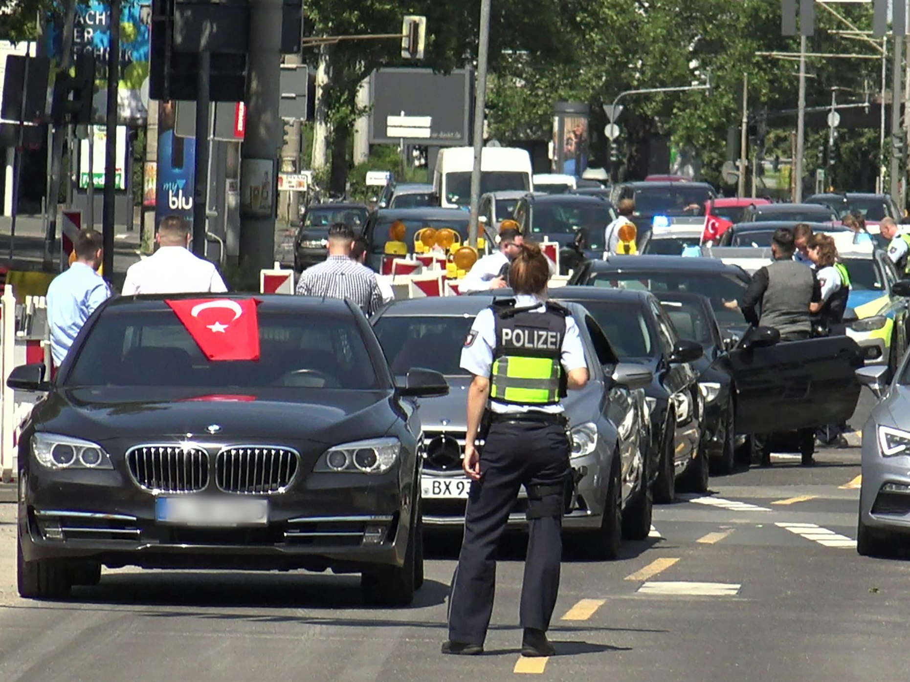 Eine Polizistin steht vor den Fahrzeugen eines angehaltenen türkischen Hochzeitskorsos.