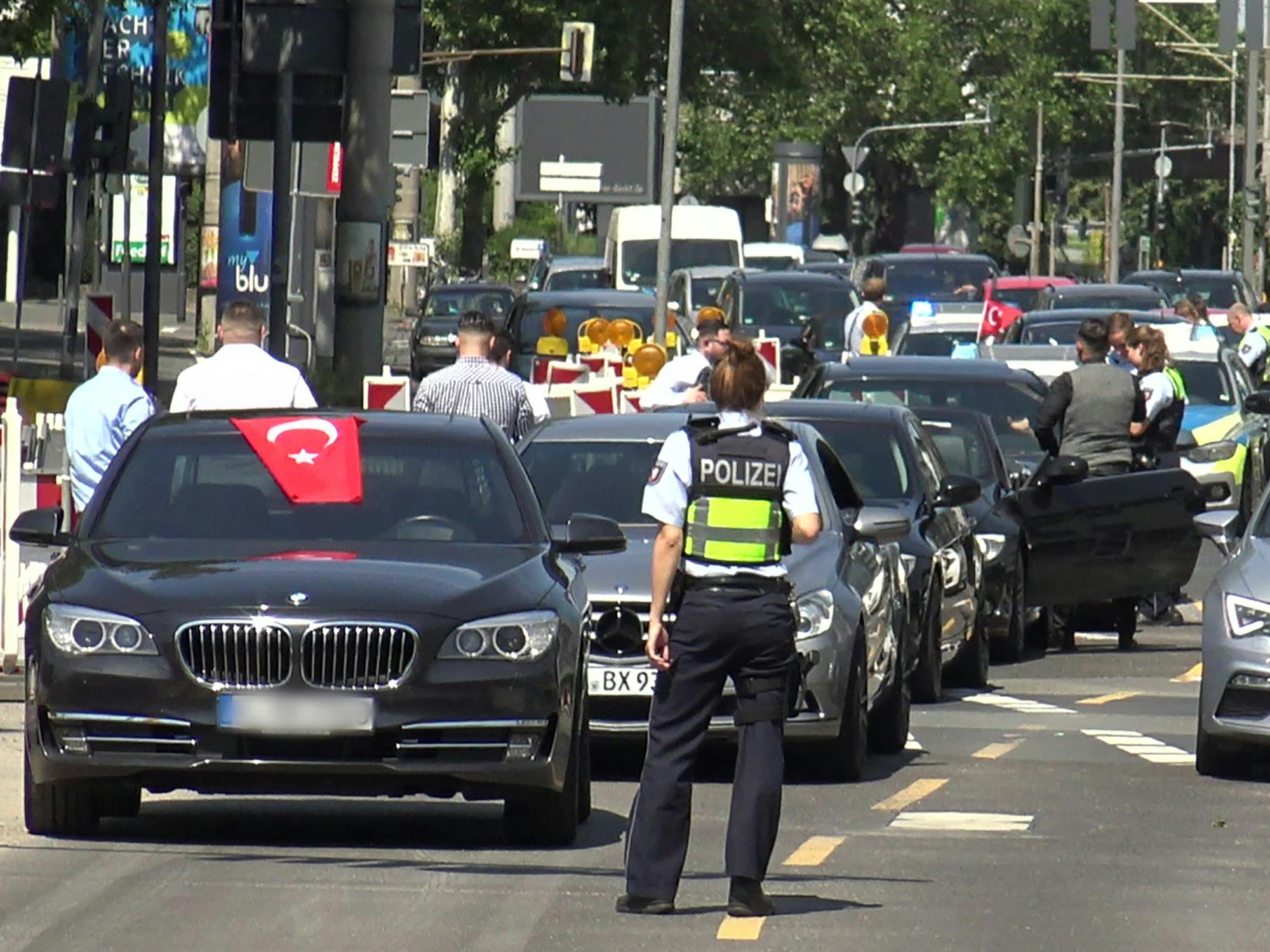 Eine Polizistin steht vor den Fahrzeugen eines angehaltenen türkischen Hochzeitskorsos.