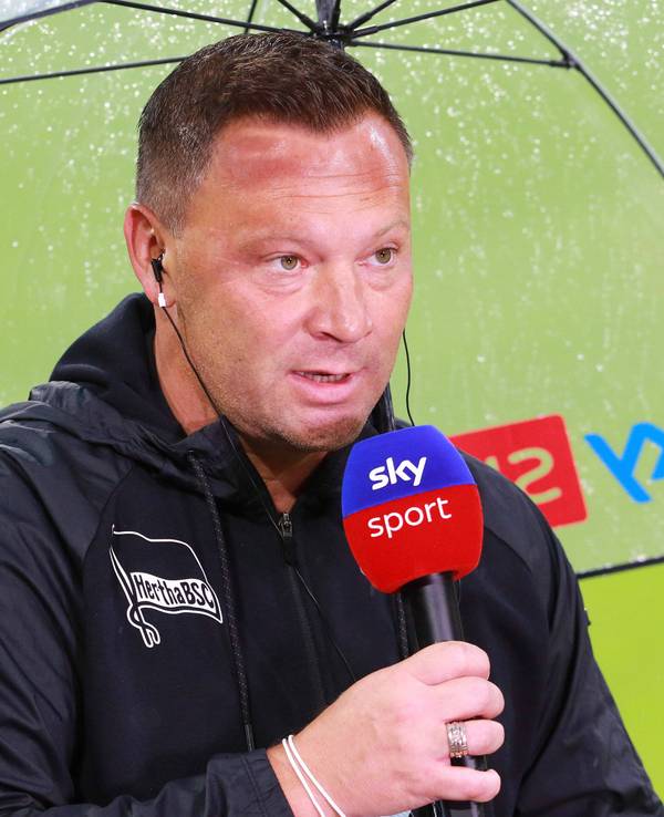 Pal Dardai steht mit einem Mikro unter einem Regenschirm.