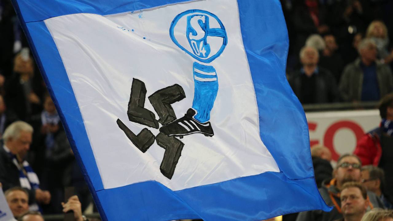 Auf einer Fahne ist ein Schalke-Wappen und ein Fuß zu sehen. Der Fuß zertritt ein Hakenkreuz.