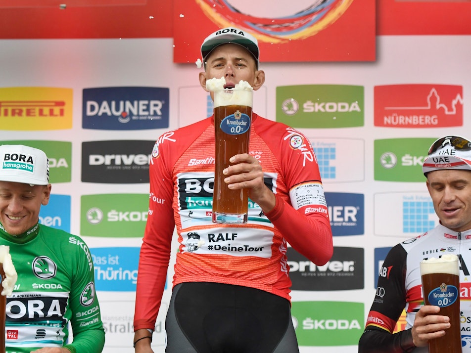 Pascal Ackermann (l-r) aus Deutschland vom Team Bora-Hansgrohe im Grünen Trikot des Sprintbesten, Nils Politt aus Deutschland vom Team Bora-Hansgrohe im Roten Trikot des Gesamtführenden und der Norweger Alexander Kristoff vom UAE Team Emirates stehen nach der Etappe auf dem Podium.